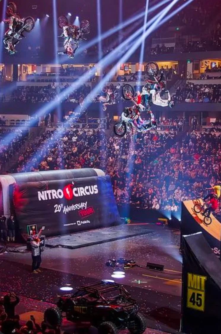 Nitro Circus riders flipping motorbikes over a packed stadium on the 20th Anniversary Tour.
